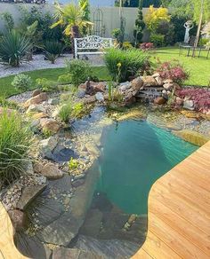 a small pond in the middle of a wooden deck next to a garden with rocks and plants