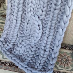 a large chunky blanket on top of a rug next to a chair and table