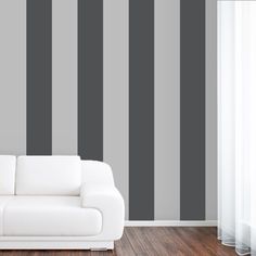 a white couch sitting in front of a gray striped wall