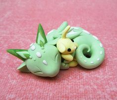 a green and white toy laying on top of a pink surface with a doughnut in the shape of a dragon