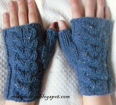 two hands wearing blue knitted gloves on top of a white blanket