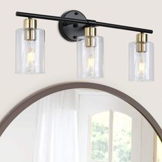 three light bathroom fixture with clear glass shades and bronze accents on the wall above mirror