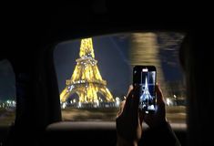 a person taking a photo of the eiffel tower at night with their cell phone