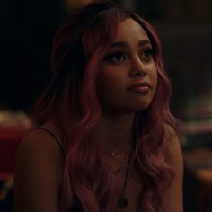 a woman with long pink hair sitting down