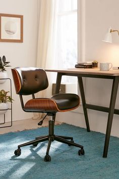 an office chair sits in front of a desk with a lamp on it and a blue rug