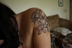 a woman with a tattoo on her arm is sitting in front of a couch and looking at the camera