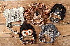 four crocheted hats with animals on them sitting on top of a wooden table