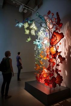 two people looking at an art piece on display in a room with light coming through the window