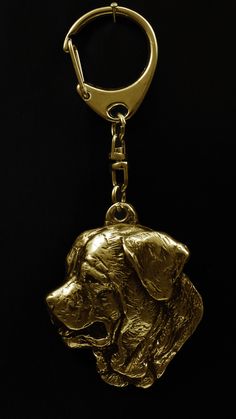 a golden metal dog keychain on a black background