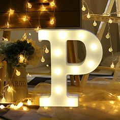 the letters p are lit up with lights and flowers in vases on the floor