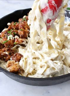 a pan filled with pasta, meatballs and sauce being stirred by a spatula