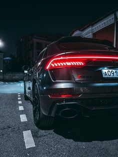 the rear end of a black sports car at night