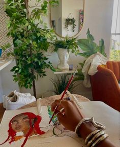 a woman is painting an elephant with red paint on the floor in front of a potted plant