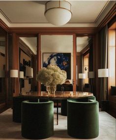 an elegant dining room with green velvet chairs and round table in front of large painting