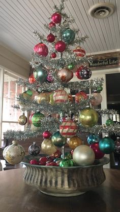 a decorated christmas tree in a potted planter with ornaments on the top and bottom