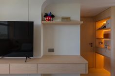 a flat screen tv sitting on top of a wooden shelf next to a wall mounted television