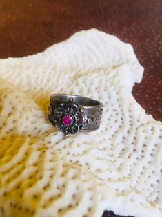 "A petite Ruby centers the flower of this vintage Lost Wax and fabricated Sterling Silver ring.  The detailed flower is multi-layered and beaded and rests upon a wide Sterling, oxidized band decorated with peek-a-boo cut outs and tiny Sterling \"nuggets.\" This vintage ring has an almost medieval feel to it and will, of course, be a lovely addition to your jewelry wardrobe or a great July birthday gift! The ring's band is 3/8 of an inch wide and the flower measures 1/2 inch x 1\".  It is a size Lost Wax Casting Rings, 14k Gold Wedding Band, Star Necklace Silver, Sterling Silver Wedding Band, Jewelry Wardrobe, Nugget Necklace, July Birthday, Diamond Free, Lost Wax Casting