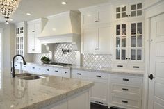 a kitchen with white cabinets and marble counter tops