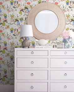 a white dresser sitting next to a wall covered in flowers