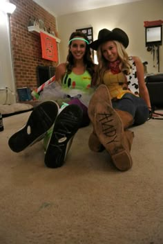 two women sitting on the floor with their feet up and one wearing a cowboy hat