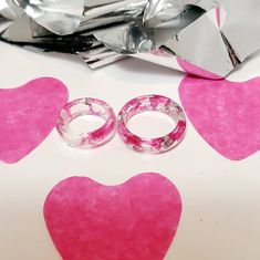 two wedding rings are sitting next to each other on a table with hearts drawn on it