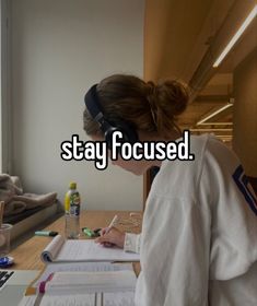 a woman sitting at a desk with headphones on writing in front of her computer