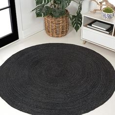 a black rug in the corner of a room next to a potted plant and window