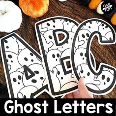 a person holding up two letters that spell out the word abc and q with pumpkins in the background