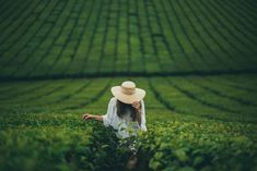 a woman wearing a hat standing in a field