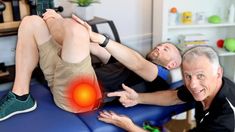 two men are sitting on a blue chair and one is pointing at an orange ball