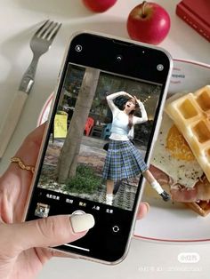 a person taking a photo of food on their cell phone while eating waffles