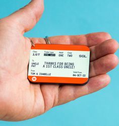 a person holding a small orange and white ticket in their left hand with the words thanks for being at 1st class inside