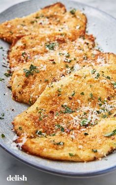 three pieces of fried food on a pan with parmesan cheese and herbs sprinkled on top