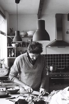 a man in the kitchen chopping vegetables on a cutting board with a knife and fork