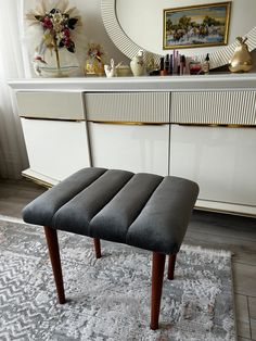 a gray bench sitting on top of a rug in front of a dresser and mirror