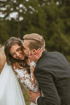 a bride and groom kissing in front of trees