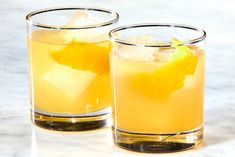 two glasses filled with drinks sitting on top of a marble counter next to each other