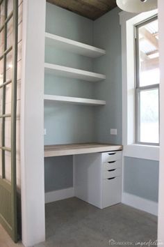 an empty room with white shelves and drawers