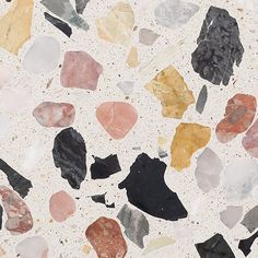 a close up of many different colored rocks on a white surface with black, red, yellow and grey colors