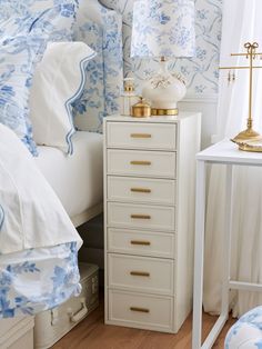 a bedroom with blue and white wallpaper, gold accents and an antique chest of drawers