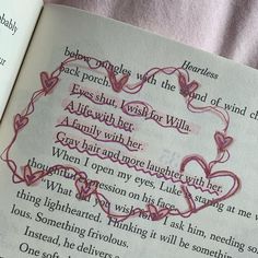 an open book with writing on it and two hearts in the middle, surrounded by pink thread