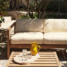 a yellow pitcher sitting on top of a wooden table next to a white and brown striped couch