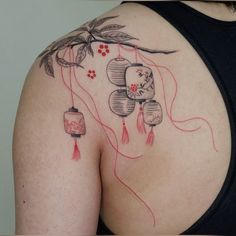 a woman's back with tattoos on her body and flowers hanging from the strings