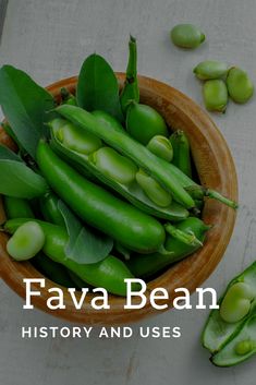 a wooden bowl filled with green beans on top of a white table next to peas