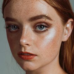 a woman with freckles on her face is looking at the camera and has blue eyes