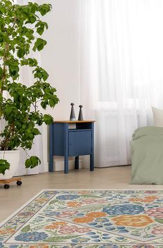 a living room with a bed, table and potted plant on the floor next to it