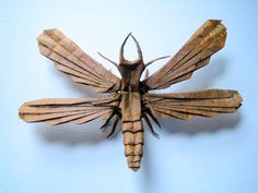 an insect made out of brown paper on a blue background