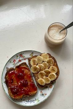 a plate with toast and bananas on it next to a glass of milk or coffee