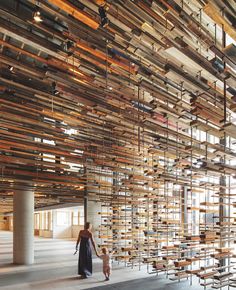 a woman walking through a large room filled with lots of wooden planks on the walls