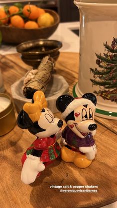 two mickey mouse figurines sitting on top of a wooden table